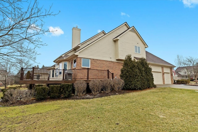 view of side of property featuring brick siding, a yard, a chimney, a deck, and driveway