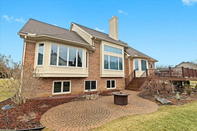 back of house featuring brick siding, a chimney, a patio area, and a wooden deck