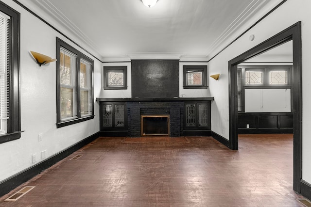 unfurnished living room with ornamental molding, a brick fireplace, visible vents, and wood finished floors