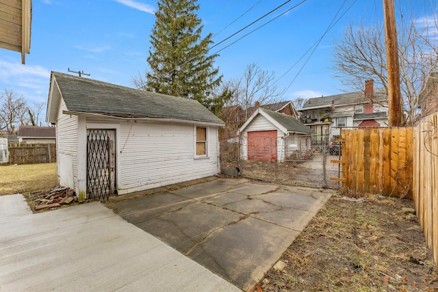 exterior space with a patio, a shingled roof, an outdoor structure, fence, and a gate