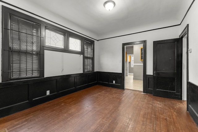 spare room featuring a wainscoted wall and hardwood / wood-style floors