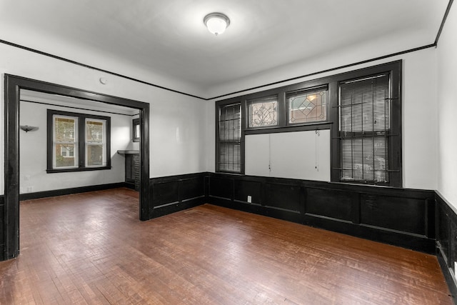 empty room with a wainscoted wall and wood-type flooring