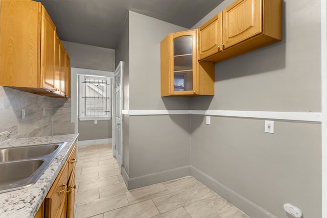 kitchen with baseboards, light countertops, glass insert cabinets, and decorative backsplash