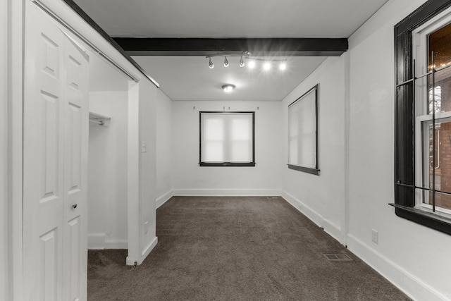 spare room with baseboards, dark carpet, visible vents, and a healthy amount of sunlight