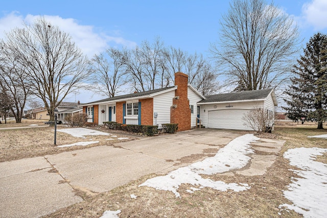 ranch-style house featuring driveway, an attached garage, a chimney, and brick siding