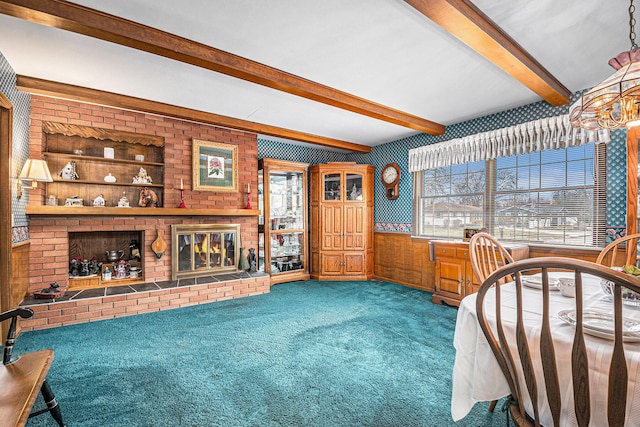 carpeted bedroom featuring wainscoting, a fireplace, beamed ceiling, and multiple windows