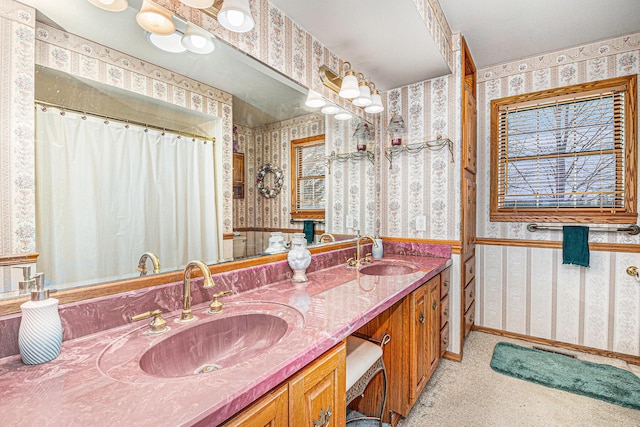 bathroom featuring double vanity, wallpapered walls, baseboards, and a sink