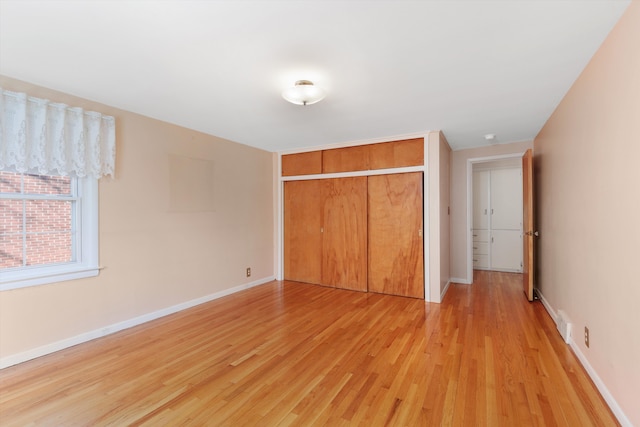 unfurnished bedroom featuring light wood-type flooring, baseboards, and a closet