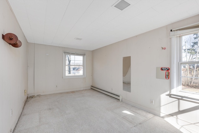 carpeted empty room featuring a baseboard heating unit and plenty of natural light