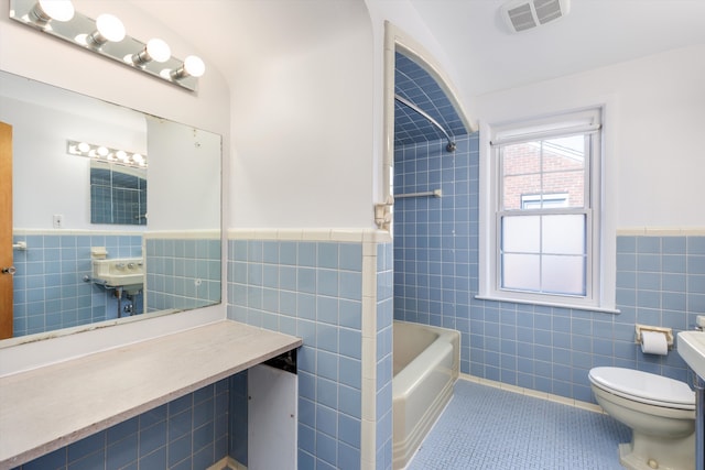 full bath with tile patterned flooring, toilet, visible vents, tile walls, and shower / washtub combination