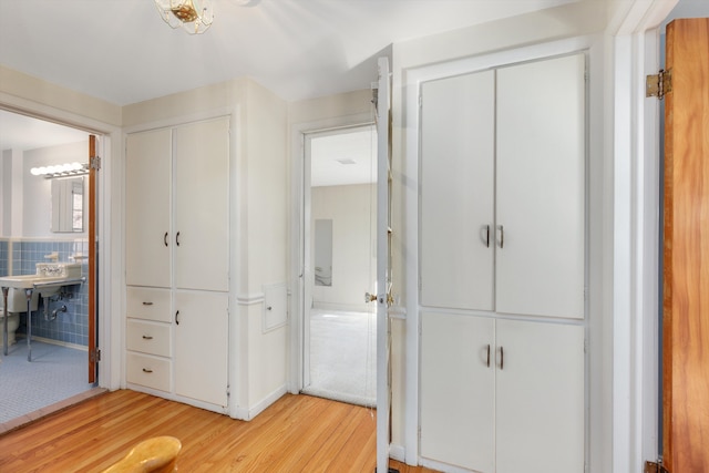 hall with light wood finished floors and tile walls