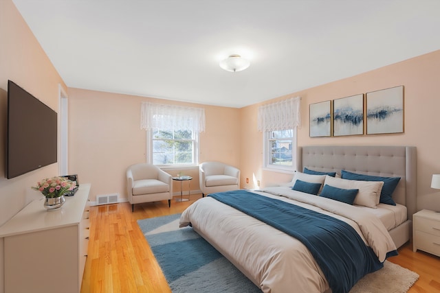 bedroom featuring light wood-style flooring, visible vents, and baseboards