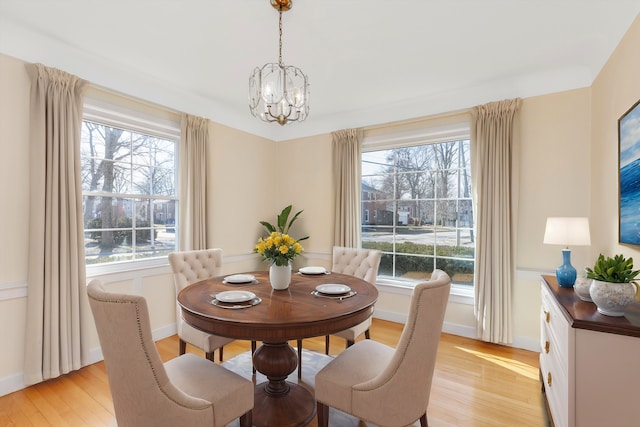 dining room featuring a notable chandelier, baseboards, and light wood-style floors