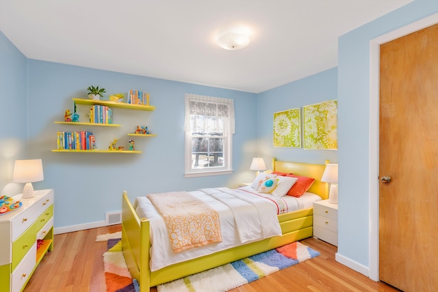 bedroom featuring visible vents, baseboards, and wood finished floors