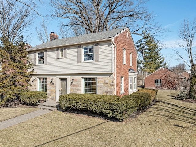 colonial inspired home with stone siding, brick siding, a chimney, and a front yard