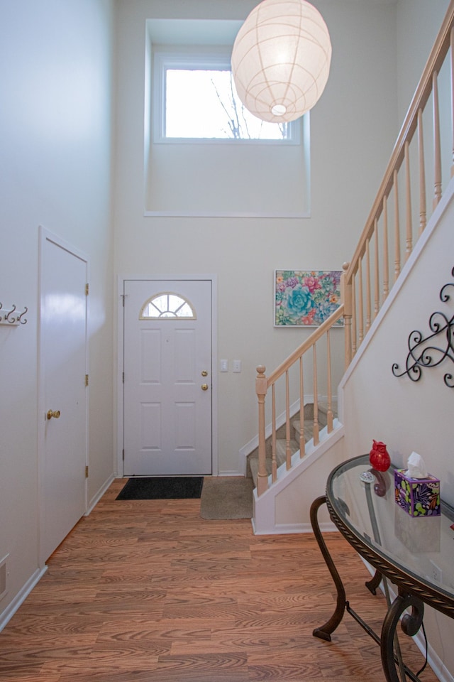 entrance foyer featuring a towering ceiling, stairway, and wood finished floors