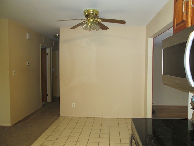 interior space with light tile patterned floors, ceiling fan, stainless steel appliances, and brown cabinetry