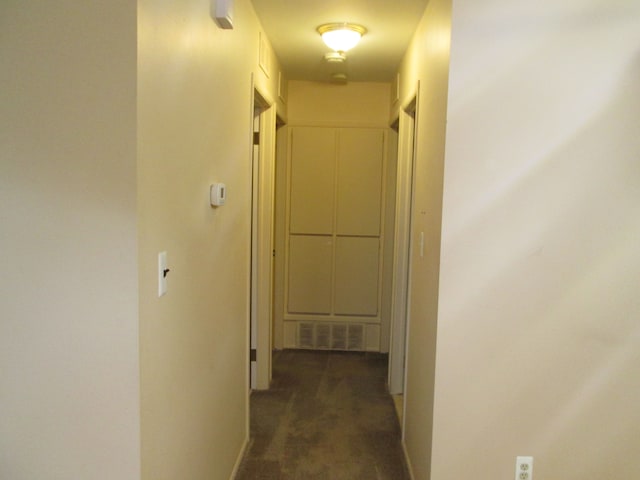 hallway with carpet floors, visible vents, and baseboards