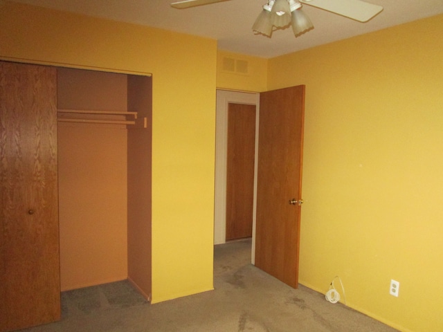 unfurnished bedroom with carpet floors, ceiling fan, visible vents, and a closet