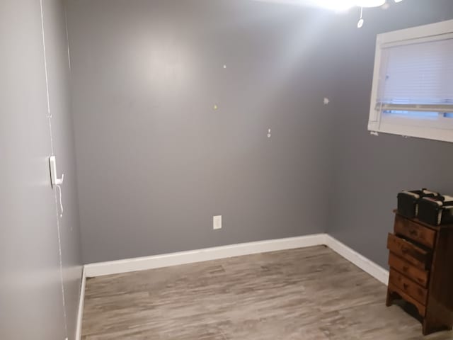 spare room with baseboards and wood finished floors