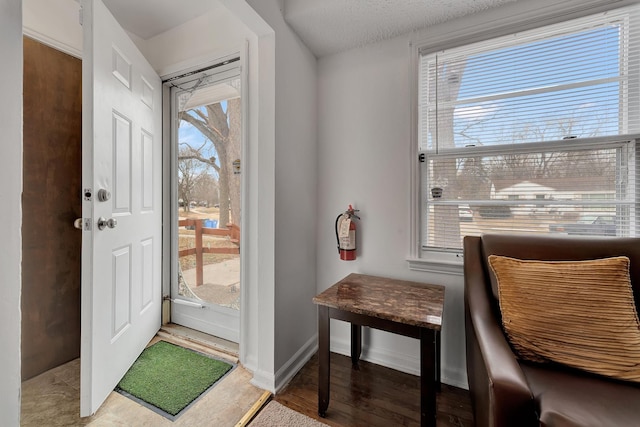 doorway with wood finished floors and baseboards