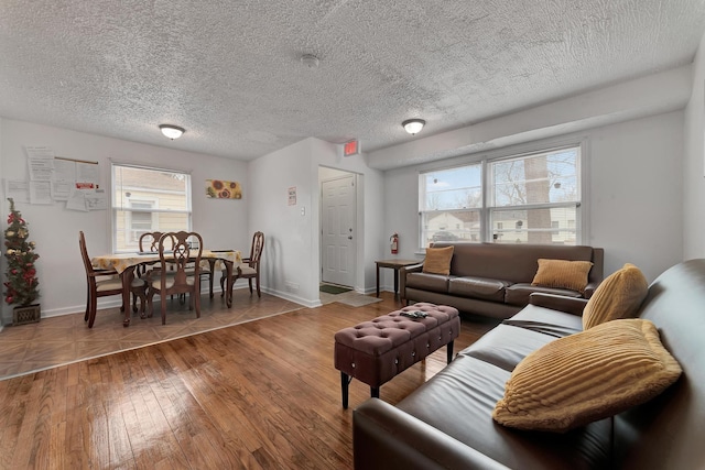 living area with a textured ceiling, hardwood / wood-style flooring, and baseboards