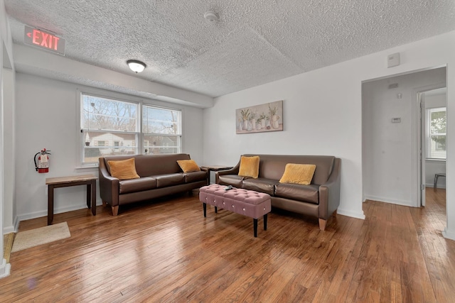 living area featuring a textured ceiling, wood-type flooring, and baseboards