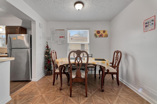 dining area with visible vents, a textured ceiling, and baseboards