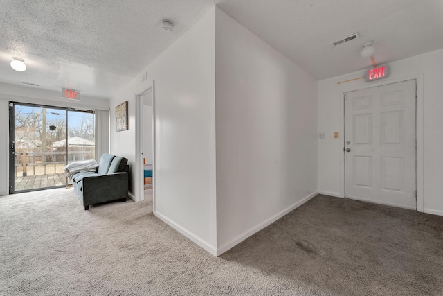 corridor with a textured ceiling, carpet floors, visible vents, and baseboards