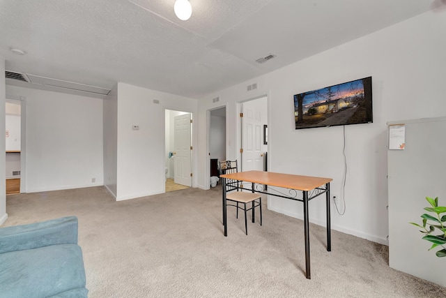 office space with light carpet, visible vents, and a textured ceiling