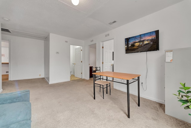 office featuring visible vents, a textured ceiling, and light colored carpet