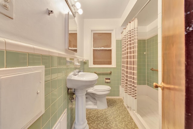 bathroom with tile walls, toilet, wainscoting, a shower stall, and tile patterned flooring