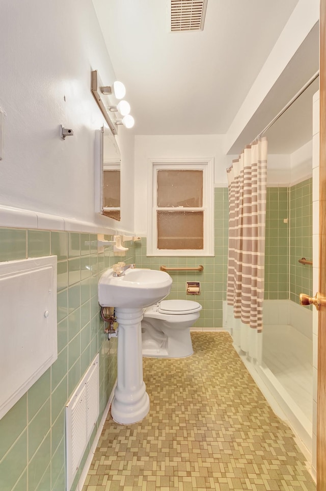 bathroom featuring tile walls, visible vents, a shower stall, and toilet