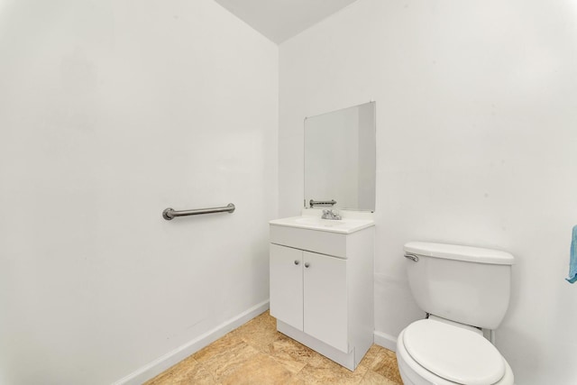 half bathroom featuring toilet, vanity, and baseboards