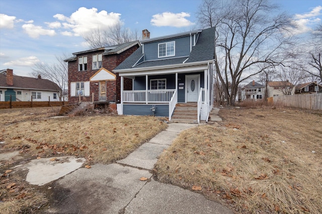 view of front of home featuring brick siding, a chimney, a porch, a shingled roof, and fence