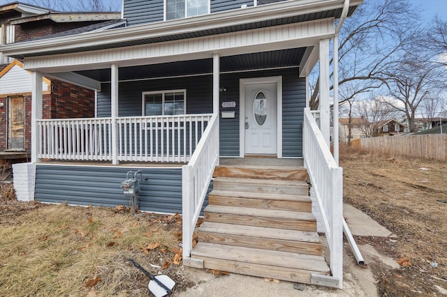 property entrance with a porch and brick siding