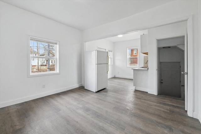 unfurnished bedroom featuring dark wood-style floors, baseboards, a sink, and freestanding refrigerator