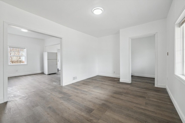 unfurnished room with a wealth of natural light, visible vents, baseboards, and wood finished floors