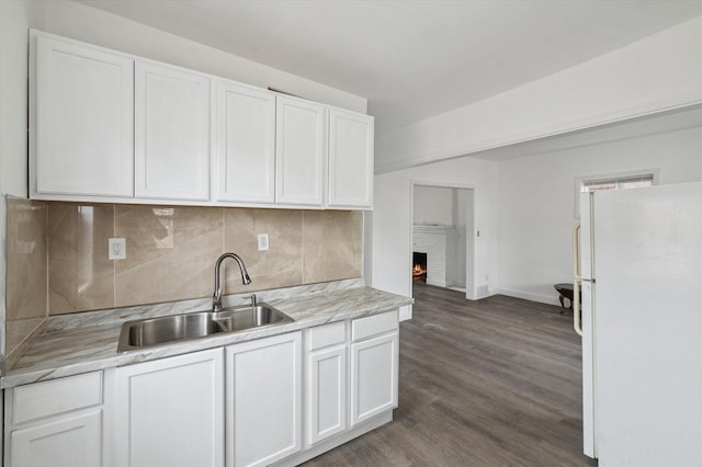 kitchen featuring light countertops, a sink, freestanding refrigerator, and white cabinetry