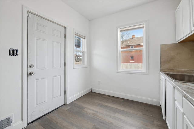 unfurnished dining area with light wood finished floors, baseboards, visible vents, and a sink