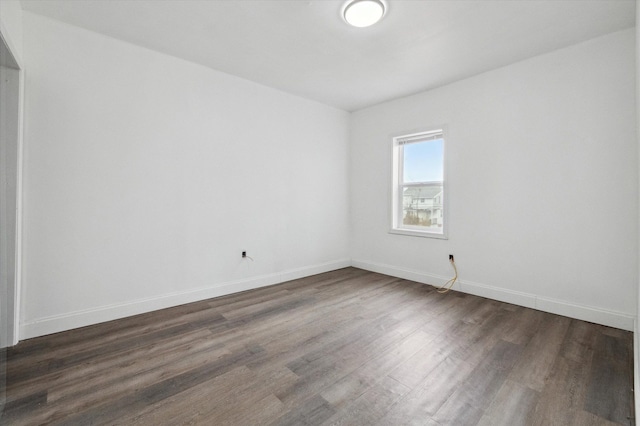 unfurnished room featuring baseboards and dark wood finished floors