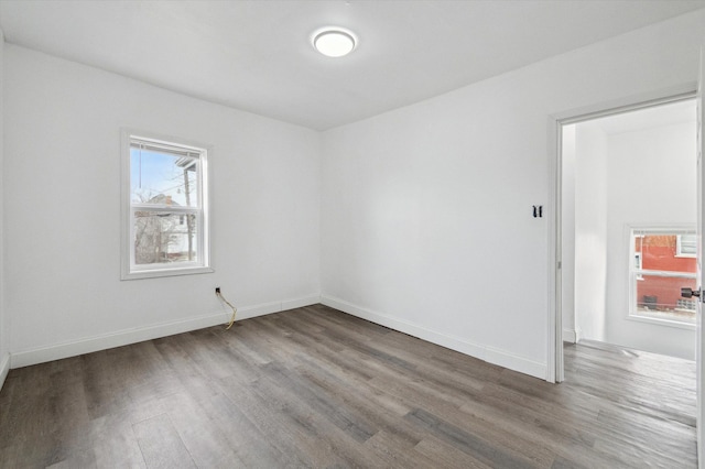 empty room featuring baseboards, a wealth of natural light, and wood finished floors