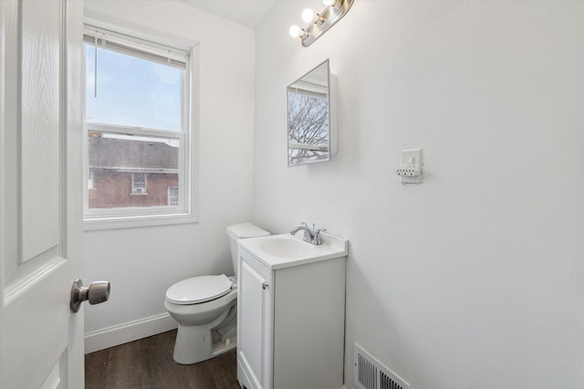 bathroom with toilet, wood finished floors, vanity, visible vents, and baseboards