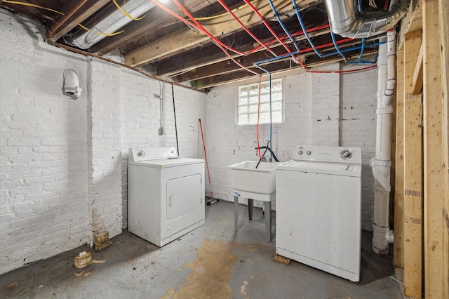 washroom featuring brick wall, laundry area, a sink, and washing machine and dryer