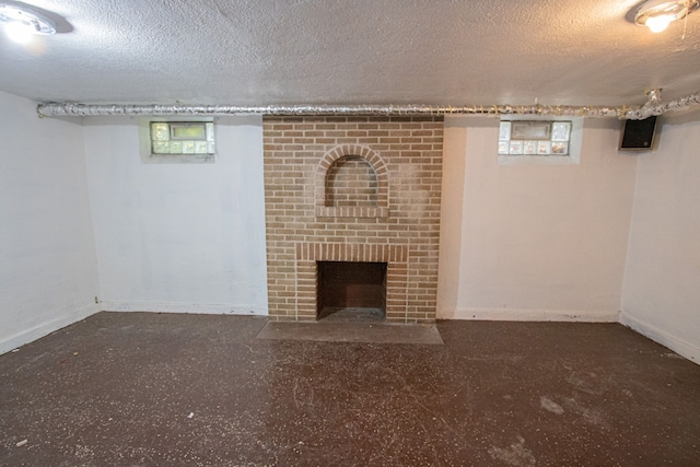 basement featuring a brick fireplace, baseboards, and a textured ceiling