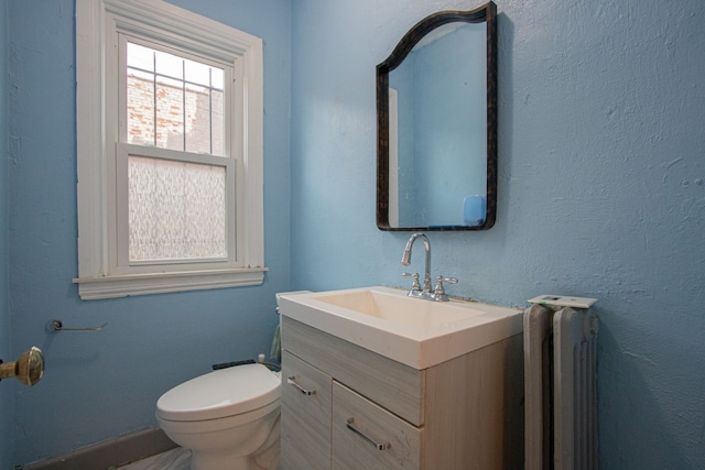 half bathroom with toilet, radiator heating unit, and vanity