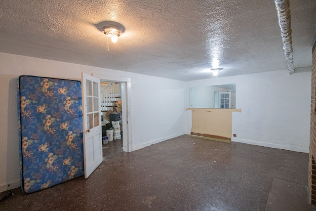 spare room featuring a textured ceiling and baseboards