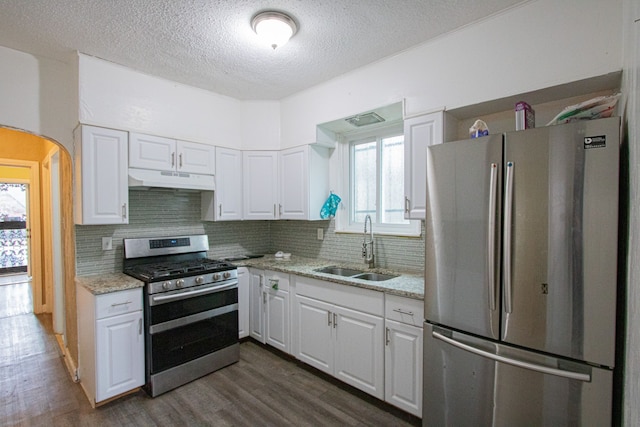 kitchen featuring under cabinet range hood, stainless steel appliances, dark wood-type flooring, a sink, and white cabinets