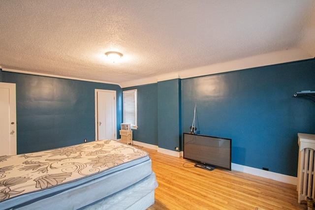 bedroom with a textured ceiling, baseboards, and wood finished floors