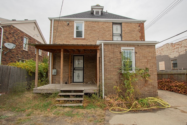 traditional style home with covered porch, brick siding, and fence